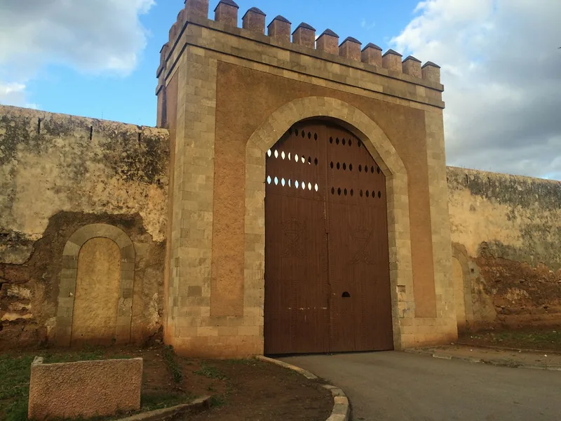 Porte de la kasbah de Témara : une grande porte en bois dans une muraille de pierre.